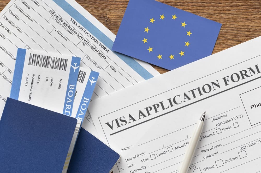 Um formulário de visto para preencher e uma bandeira da União Europeia representando que a tradução juramentada é requerida nos processos de obtenção da cidadania europeia.